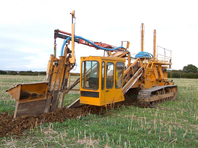 Verlegung von Rohrdrainage in einem ausgehobenen Graben auf landwirtschaftlichem Boden
